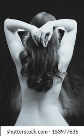 A Black And White Vintage Styled Photograph Of A Young Woman's Naked Back, Her Hands Behind Her Head