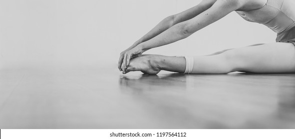 Black and white wallpaper faceless ballet dancer warming up in studio copy space room for text. No face dancing female feet legs stretching indoors toes professional arts. Modern contemporary art - Powered by Shutterstock