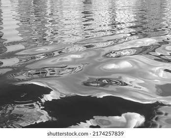 Black And White Water Reflex Background. Abstract Reflection And Inspection Elements In Water. City, Buildings Elements Distorted In The River. Rippled Water Texture. Disordered Clouds Surface