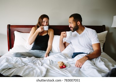 Black And White Young Couple Drinking Coffee In Bed Together