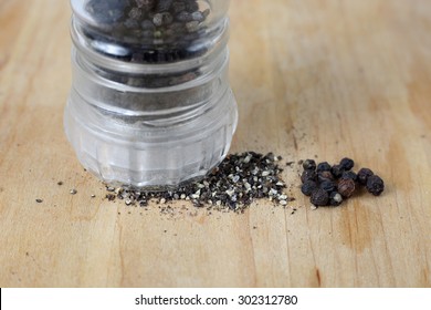 Black Whole Peppercorns And Ground Pepper With Grinder For Spices On Wooden Cutting Board