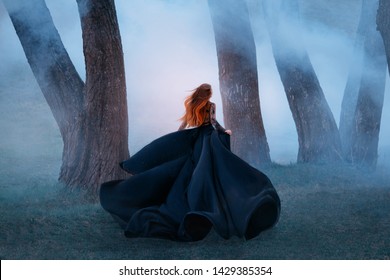 black widow long dark silk fly fabric dress, scary horror woman red hair runs mystery forest turned away black lady night walk gothic blue fog nature tree. art photo shoot mysterious woman silhouette - Powered by Shutterstock