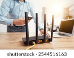 Black wifi router with four antennas. Man using smart phone with fast wireless network