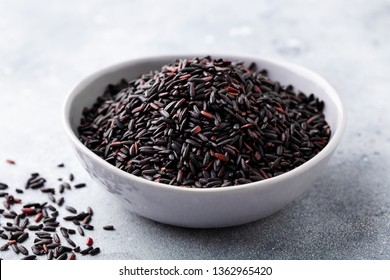 Black wild rice in a bowl. Grey stone background. Close up.