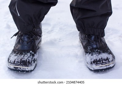 Black winter boots stand on the snow