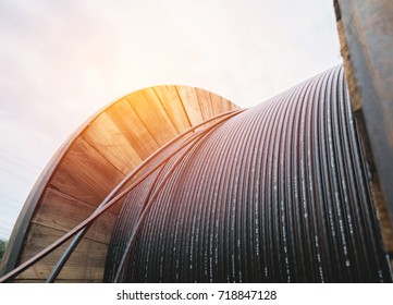 black wire  electric cable with wooden coil of electric cable under the sky.