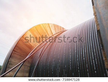 black wire  electric cable with wooden coil of electric cable under the sky.