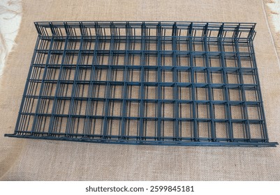 Black wire mesh grid, rectangular in shape, with a large surface area and a solid color background.