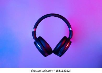 Black Wireless Bluetooth Headphones On Neon Light Background. Music Concept.