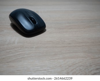 Black wireless computer mouse on wooden surface