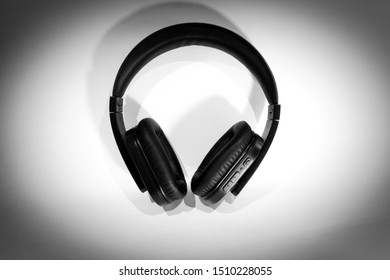Black wireless headphones on white background with dark vignette. Modern Bluetooth over-ear headphones