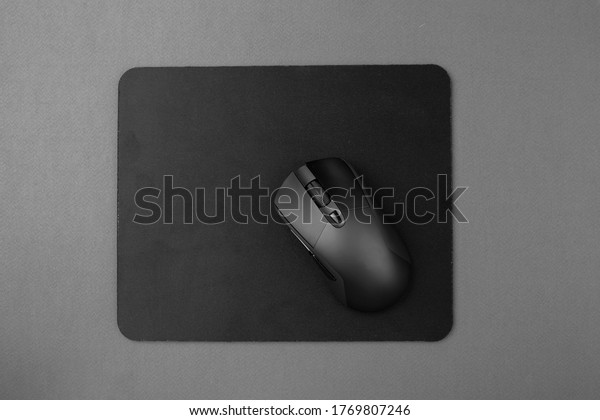 Black wireless\
mouse on a mouse pad, top\
view.