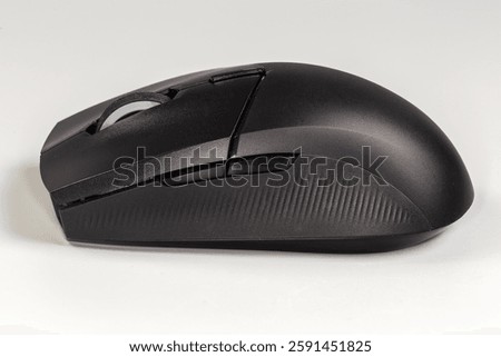 Black wireless optical computer mouse with scroll wheel and additional side buttons on a gray background, side view close-up 