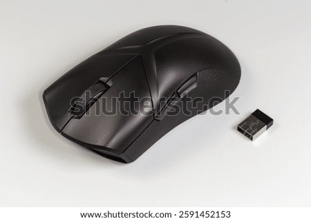 Black wireless optical computer mouse with scroll wheel and additional side buttons and USB receiver on a gray background