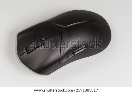 Black wireless optical computer mouse with scroll wheel and additional side buttons on a gray background, top view close-up