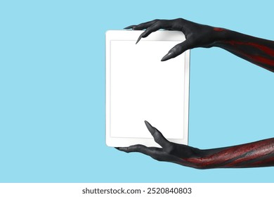 Black witch hands with claws and tablet on blue background. Halloween celebration - Powered by Shutterstock