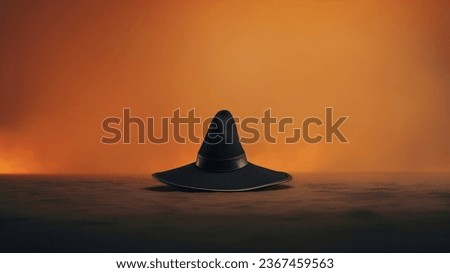 A black witch's hat placed on the ground along with an orange background.