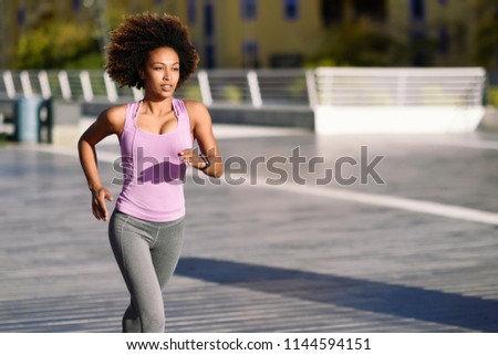 Black woman afro hairstyle running outdoors in urban road