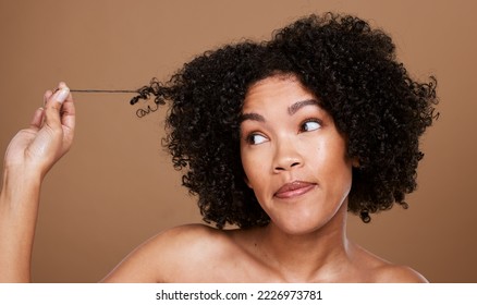 Black woman afro, messy hair and curls looking for cosmetics or salon treatment against a brown studio background. African American female in hair care holding entangled strand on mockup