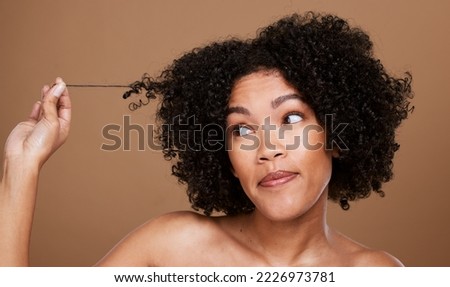 Black woman afro, messy hair and curls looking for cosmetics or salon treatment against a brown studio background. African American female in hair care holding entangled strand on mockup