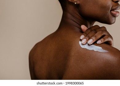 Black woman applying body cream - Shutterstock ID 1998300065