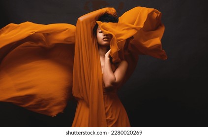 Black woman, art and fashion, fabric movement on dark background with beauty and aesthetic motion. Flowing silk, fantasy and artistic, serious African model in brown creative designer dress in studio - Shutterstock ID 2280020269