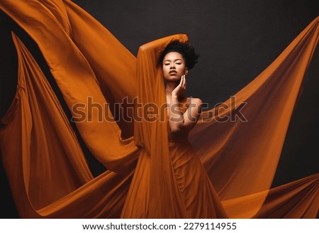 Black woman, art and fashion, flowing fabric on dark background with beauty and aesthetic movement. Silk, fantasy and artistic portrait of serious African model in creative designer dress in studio.