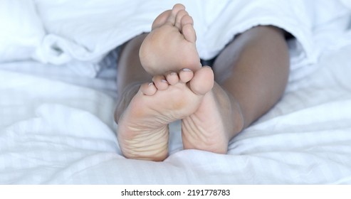 Black Woman Bare-feet Take A Rest In Bed. African American Female Legs.