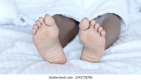 Black Woman Bare-feet Take A Rest In Bed. African American Female Legs.