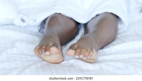 Black Woman Bare-feet Take A Rest In Bed. African American Female Legs.