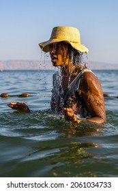 black woman bathing in sea of galilee srael. water dripping and splashing as she enjoys lake tiberius and sun.