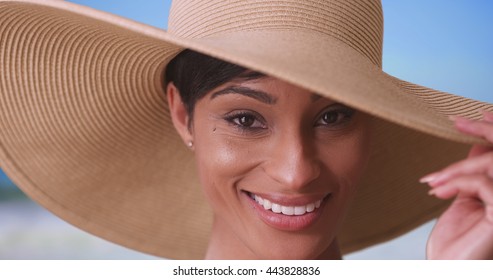 Black woman with big sunhat looking at camera and smiling
