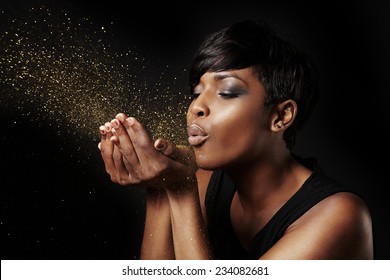 black woman blowing golden dust. Make a wish concept