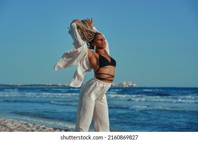 Black Woman With Braids Walking On The Beach Barefoot, Spending The Vacations Posing In The Wind. Horizontal Photo