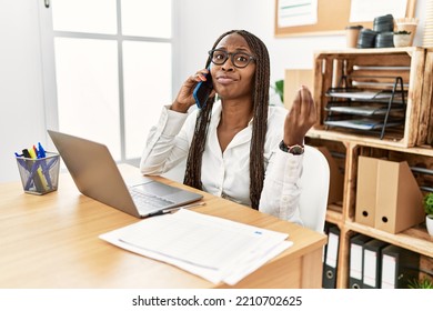 Black Woman With Braids Working At The Office Speaking On The Phone Doing Italian Gesture With Hand And Fingers Confident Expression 