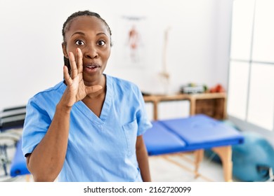 Black Woman With Braids Working At Pain Recovery Clinic Hand On Mouth Telling Secret Rumor, Whispering Malicious Talk Conversation 