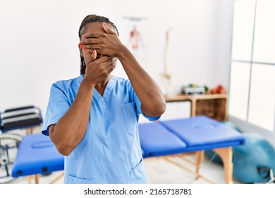 Black Woman With Braids Working At Pain Recovery Clinic Covering Eyes And Mouth With Hands, Surprised And Shocked. Hiding Emotion 