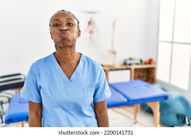 Black Woman With Braids Working At Pain Recovery Clinic Puffing Cheeks With Funny Face. Mouth Inflated With Air, Crazy Expression. 