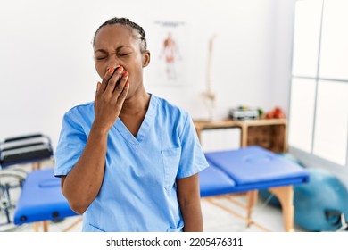 Black Woman With Braids Working At Pain Recovery Clinic Bored Yawning Tired Covering Mouth With Hand. Restless And Sleepiness. 