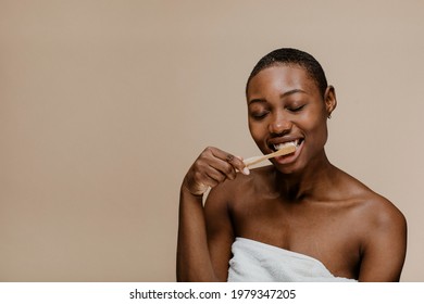 Black Woman Brushing Her Teeth With A Wooden Toothbrush