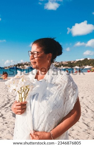 Black woman celebrating February 2nd, Yemanja festival, tossing flowers on the beach. Brazil traditional celebration 