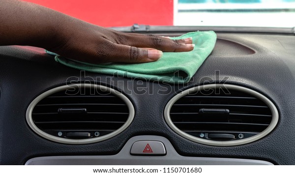 Black woman\
cleaning car interior with green microfiber cloth.  Polishing car\
interior dashboard for car wash\
concept