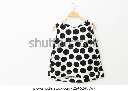 Black woman clothes on a hanger with a polka dot pattern.