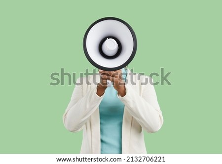 Black woman covering her face with megaphone and making announcement. Studio shot of American lady hiding her head behind loudspeaker and spreading important message with her loud amplified voice