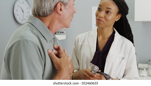 Black woman doctor listening to senior patient talking