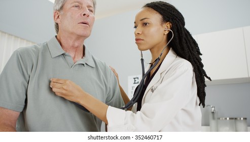 Black Woman Doctor Listening To Senior Breathing