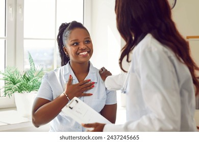 Black woman doctor or nurse is talking with a happy patient in a hospital. The atmosphere is one of genuine care, with the medical professional engaging in a conversation. - Powered by Shutterstock