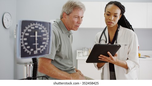 Black Woman Doctor Talking With Senior Patient In The Office