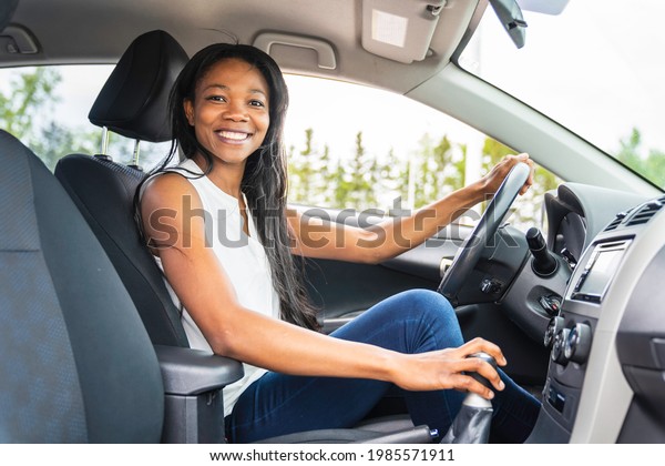 A black woman\
driver seated in her new car