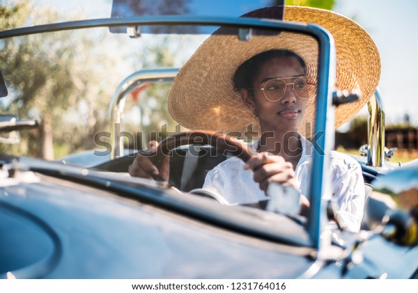 Black woman\
driving a vintage convertible\
car